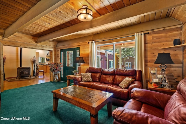 carpeted living room featuring wooden ceiling, wood walls, beamed ceiling, and a wood stove