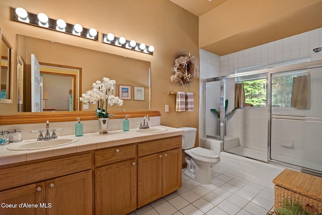 full bath with toilet, tile patterned floors, shower / bath combination with glass door, and a sink