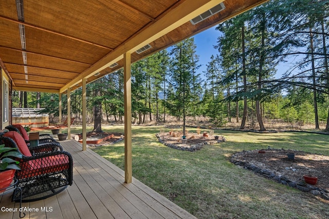 wooden deck featuring visible vents and a lawn