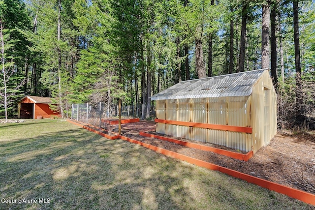 view of yard with a garden, an outbuilding, a forest view, and an exterior structure