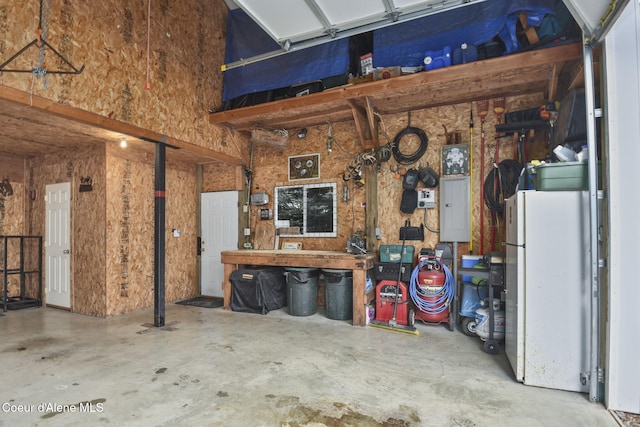 5758 E Burma Rd, Harrison, ID 83833 - garage featuring freestanding refrigerator, a workshop area, and electric panel
