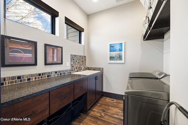 7431 E Cumberland Ct, Hayden, ID 83835 - washroom featuring dark wood-style flooring, baseboards, independent washer and dryer, cabinet space, and a sink