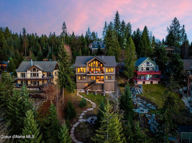 7431 E Cumberland Ct, Hayden, ID 83835 - back of property at dusk featuring a wooded view and a balcony