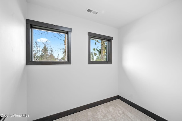 unfurnished room featuring a healthy amount of sunlight, carpet flooring, baseboards, and visible vents