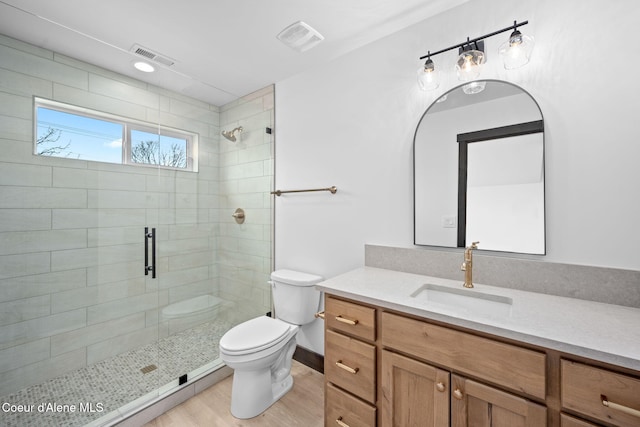 bathroom featuring a shower stall, visible vents, toilet, and wood finished floors