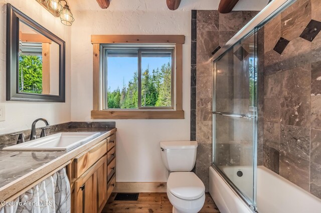 164 Generations Dr, Athol, ID 83801 - bathroom with baseboards, combined bath / shower with glass door, toilet, vanity, and wood finished floors