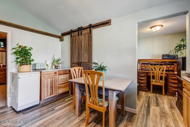 dining room featuring light wood finished floors, a barn door, and lofted ceiling