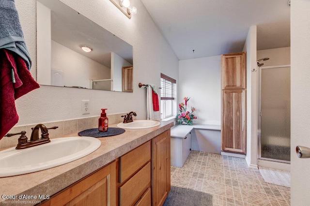 bathroom featuring a shower stall, double vanity, a sink, and vaulted ceiling