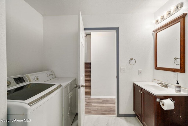 washroom with laundry area, marble finish floor, washing machine and clothes dryer, a sink, and baseboards