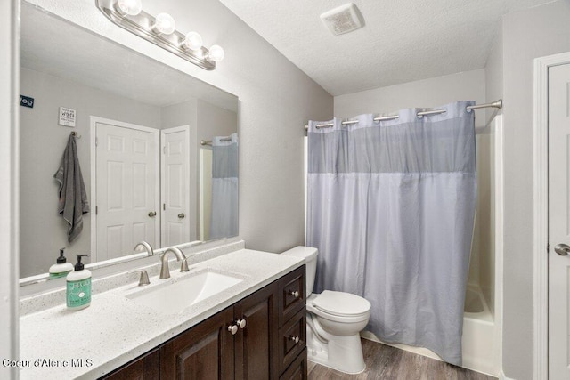 full bath featuring vanity, a textured ceiling, toilet, visible vents, and wood finished floors