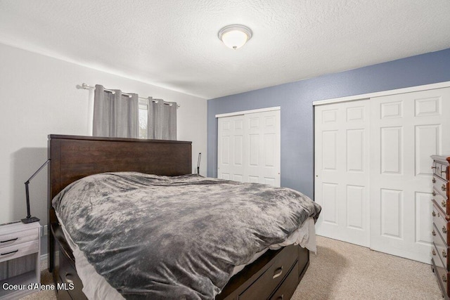 carpeted bedroom featuring multiple closets and a textured ceiling
