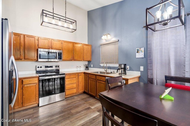 kitchen featuring a sink, light countertops, appliances with stainless steel finishes, dark wood finished floors, and pendant lighting