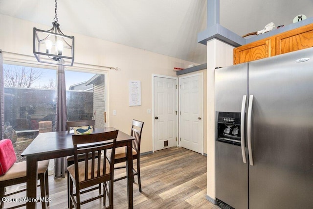 dining room with vaulted ceiling, light wood-type flooring, and an inviting chandelier