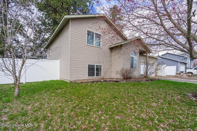 view of side of home with fence and a lawn
