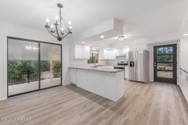 kitchen featuring light wood finished floors, a sink, a peninsula, a chandelier, and stainless steel appliances