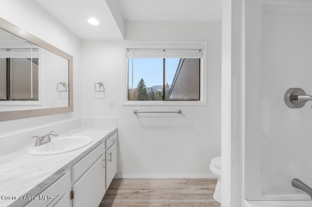 bathroom with toilet, baseboards, vanity, and wood finished floors