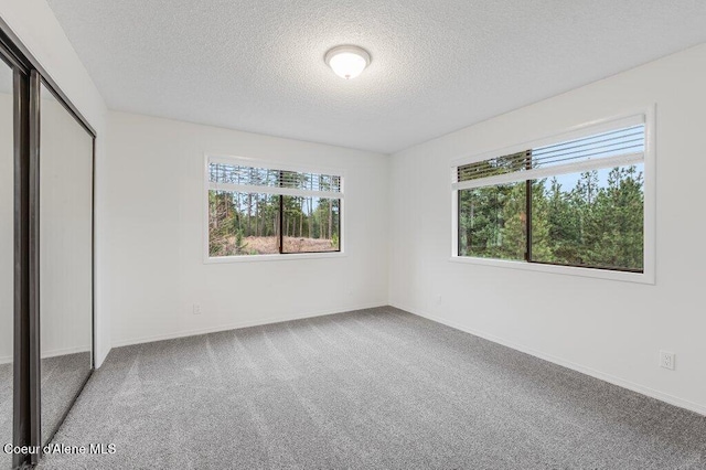 unfurnished bedroom featuring carpet, baseboards, a closet, and a textured ceiling