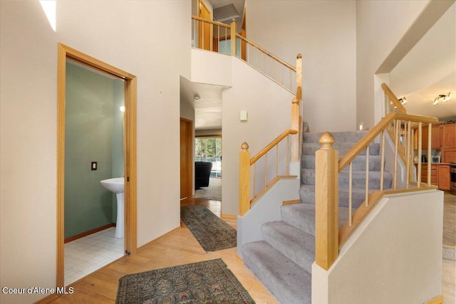 staircase with wood finished floors, a high ceiling, and baseboards