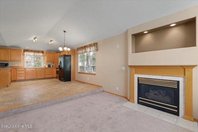 kitchen with light countertops, freestanding refrigerator, a fireplace, stainless steel microwave, and lofted ceiling