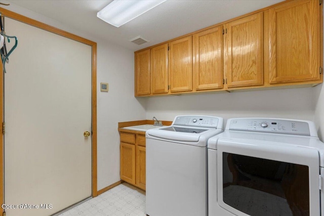 laundry room featuring visible vents, washer and clothes dryer, cabinet space, light floors, and a sink