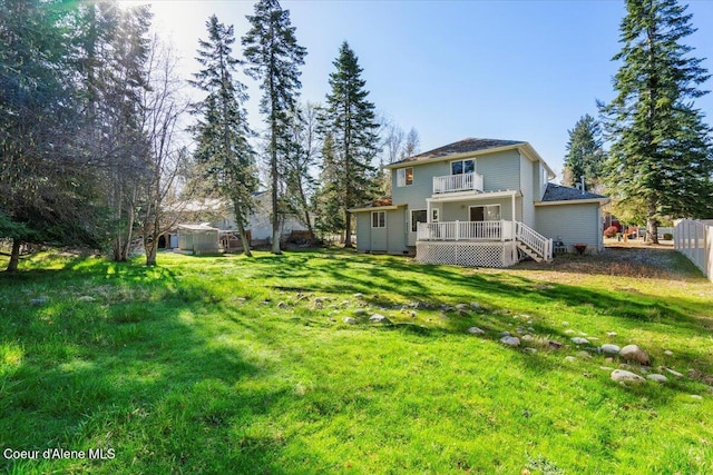 back of property featuring a yard, a balcony, an outdoor structure, and fence