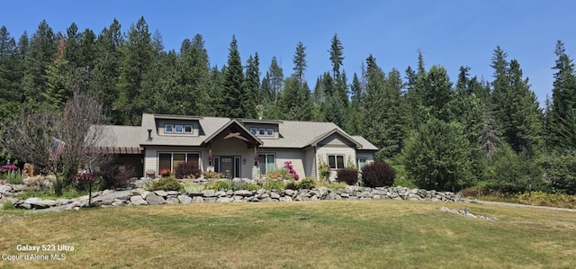 view of front of property featuring a front yard and a view of trees