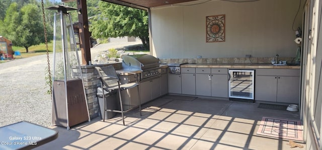 view of patio with grilling area, wine cooler, a sink, and exterior kitchen