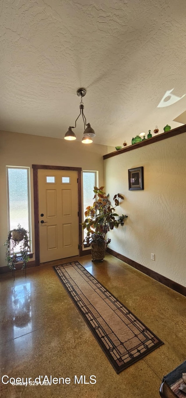 foyer entrance with a wealth of natural light, baseboards, a textured ceiling, and speckled floor