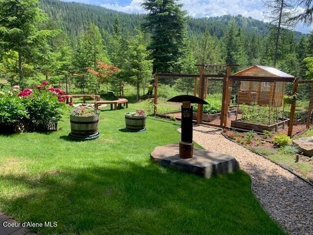 137 Bitterroot Pass, Sagle, ID 83860 - view of yard featuring an outdoor structure, a forest view, and a vegetable garden