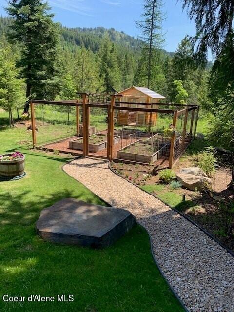 137 Bitterroot Pass, Sagle, ID 83860 - exterior space with an outbuilding, a garden, a view of trees, and a lawn