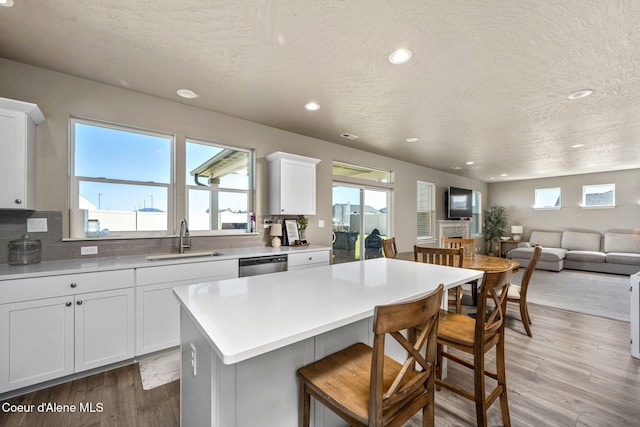 4209 May Ella Lp, Post Falls, ID 83854 - kitchen with light wood finished floors, dishwasher, a sink, a kitchen bar, and a textured ceiling