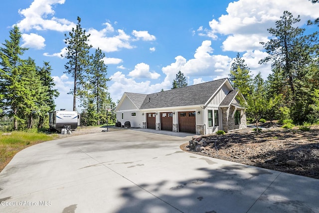 view of side of property with concrete driveway, board and batten siding, a garage, and stone siding