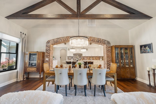 dining room with arched walkways, wood finished floors, an inviting chandelier, and beamed ceiling
