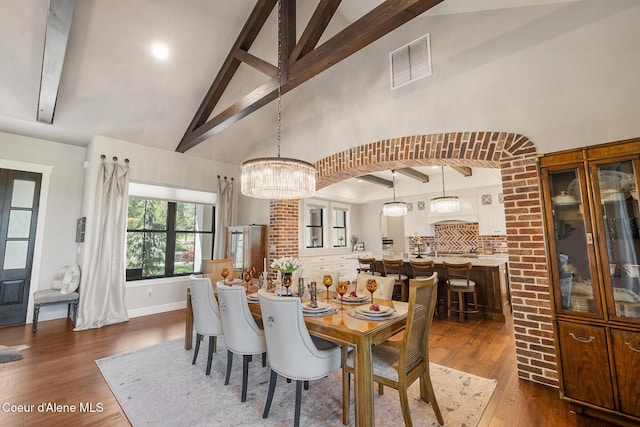 dining space with visible vents, dark wood-style flooring, a chandelier, beam ceiling, and high vaulted ceiling