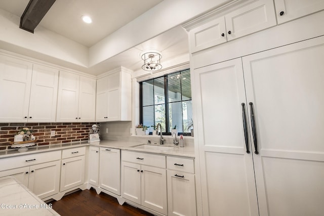 kitchen featuring paneled dishwasher, dark wood-style floors, white cabinetry, backsplash, and a sink