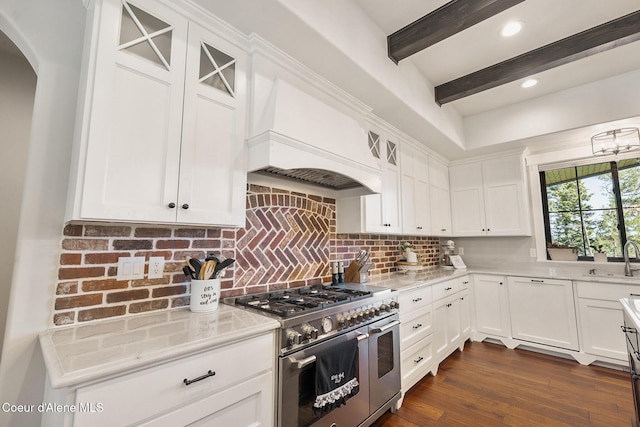 kitchen featuring white cabinets, arched walkways, range with two ovens, and a sink