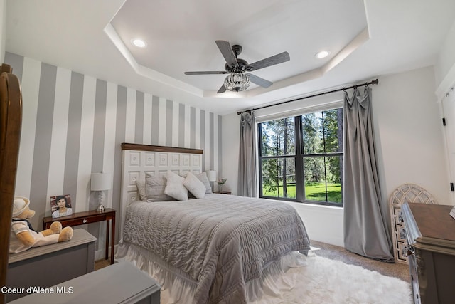 carpeted bedroom featuring a tray ceiling, ceiling fan, recessed lighting, and wallpapered walls