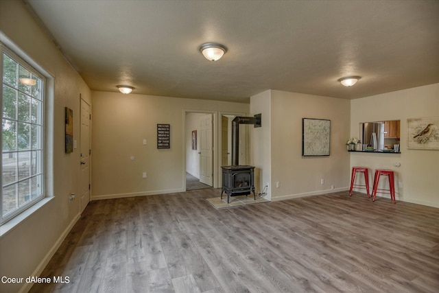 1813 N Spokane St, Post Falls, ID 83854 - unfurnished living room featuring a wood stove, baseboards, and wood finished floors