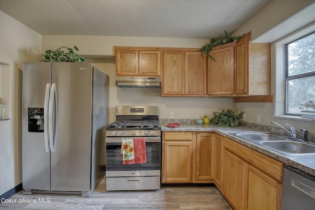 1813 N Spokane St, Post Falls, ID 83854 - kitchen featuring a textured ceiling, appliances with stainless steel finishes, under cabinet range hood, a sink, and light wood finished floors