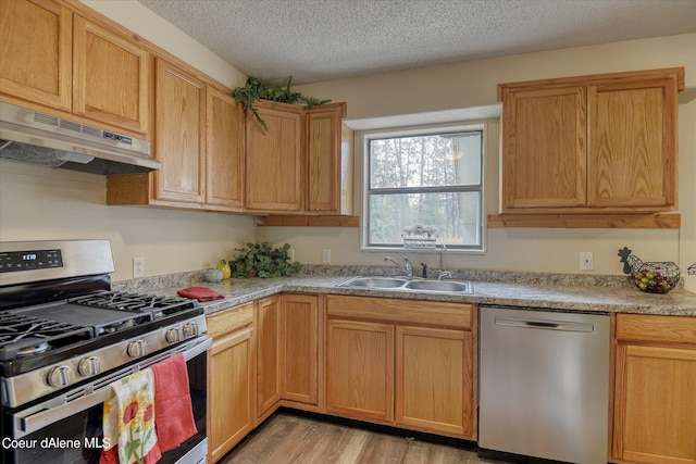 1813 N Spokane St, Post Falls, ID 83854 - kitchen featuring a sink, light wood-type flooring, a textured ceiling, under cabinet range hood, and stainless steel appliances