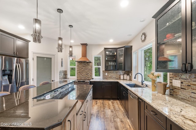 26 Hanaford Rd, Blanchard, ID 83804 - kitchen featuring a sink, wall chimney range hood, appliances with stainless steel finishes, decorative backsplash, and light wood finished floors