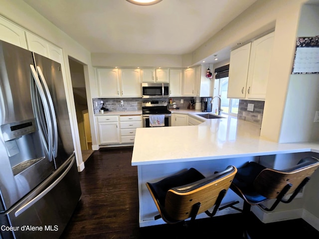 kitchen with white cabinets, stainless steel appliances, a peninsula, and a sink
