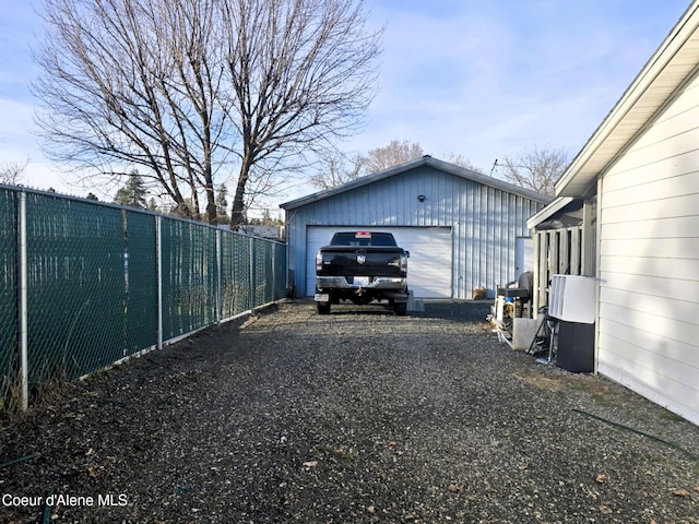 exterior space featuring an outdoor structure, a detached garage, and fence
