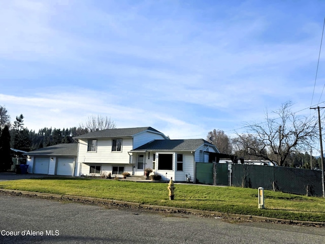split level home featuring a front lawn, fence, aphalt driveway, and an attached garage