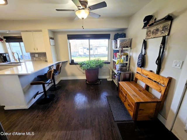 home office featuring dark wood-type flooring, a ceiling fan, baseboards, and a sink