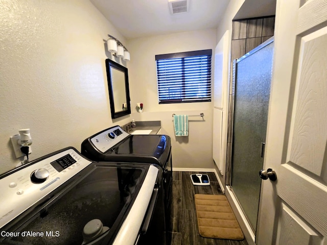 laundry area with washer and clothes dryer, a sink, dark wood-style flooring, visible vents, and laundry area