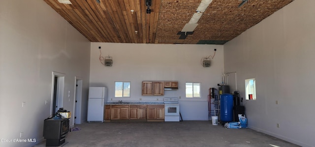 interior space with baseboards, white appliances, a high ceiling, and a sink