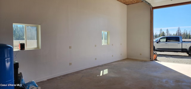 interior space featuring baseboards, a high ceiling, and unfinished concrete floors