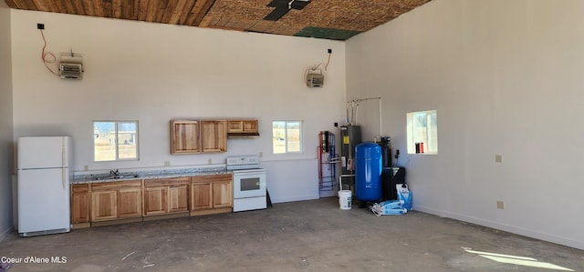 kitchen with a sink, baseboards, white appliances, and a high ceiling