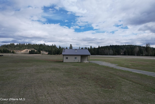 exterior space featuring a forest view and a front lawn